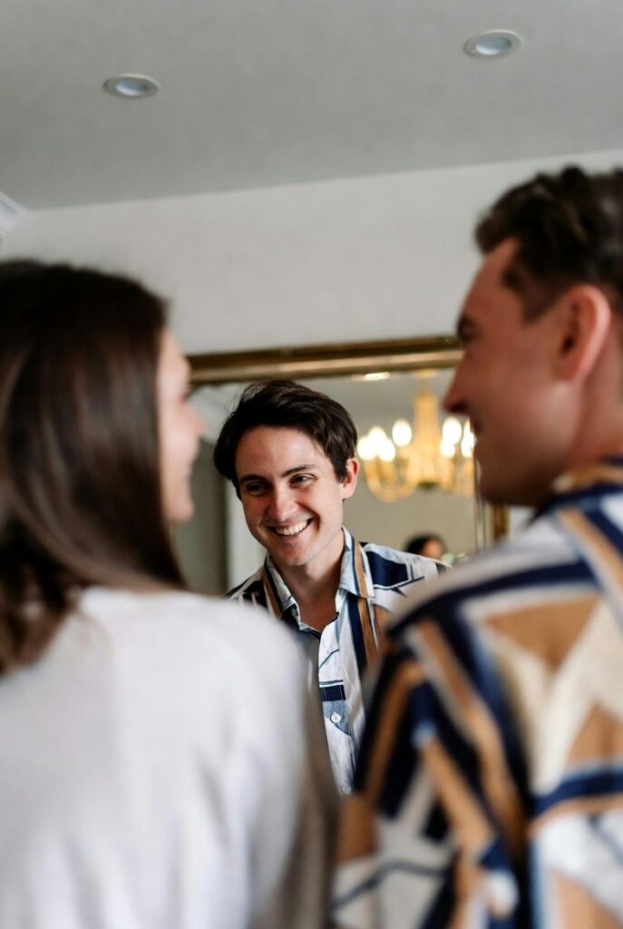 Smiling young adults looking at their reflections in a mirror.