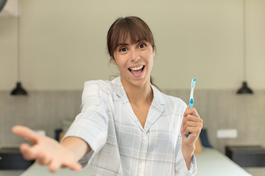 Woman holding a toothbrush and smiling about her oral health.
